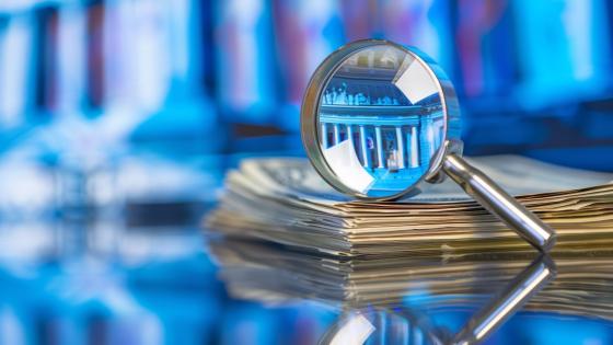 Magnifying glass inspecting stack of financial documents